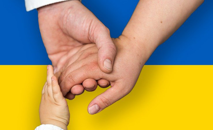 Mains enfant et adulte jointes sur drapeau de l'Ukraine