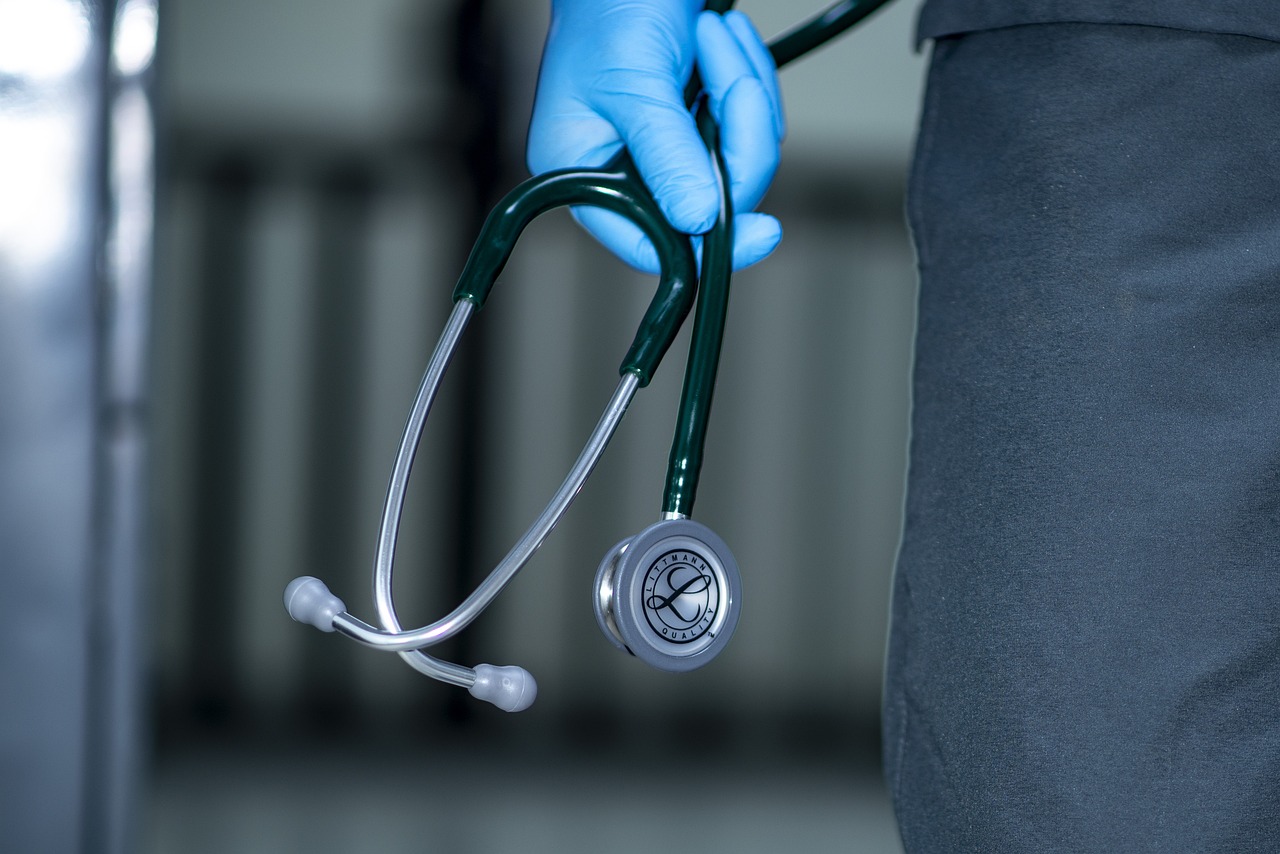 Gros plan sur les gants bleus d'un professionnel de santé qui tient un stéthoscope