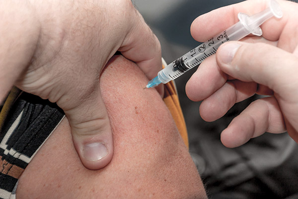 Gros plan sur vaccination : seringue qui pique epaule